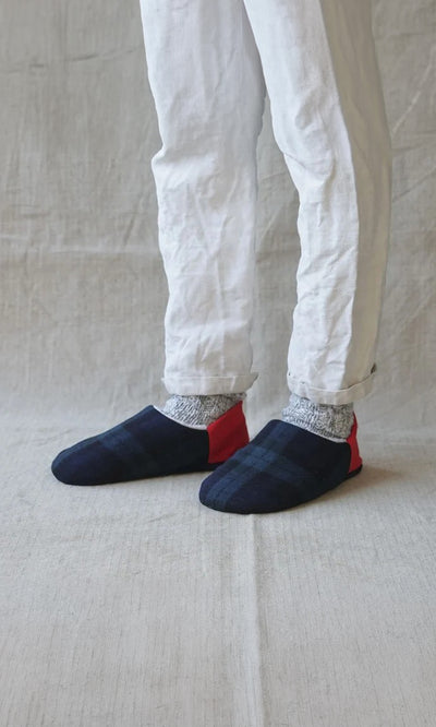 Plümo  Person in white pants, gray socks, and Tartan Slippers stands on a light fabric surface.