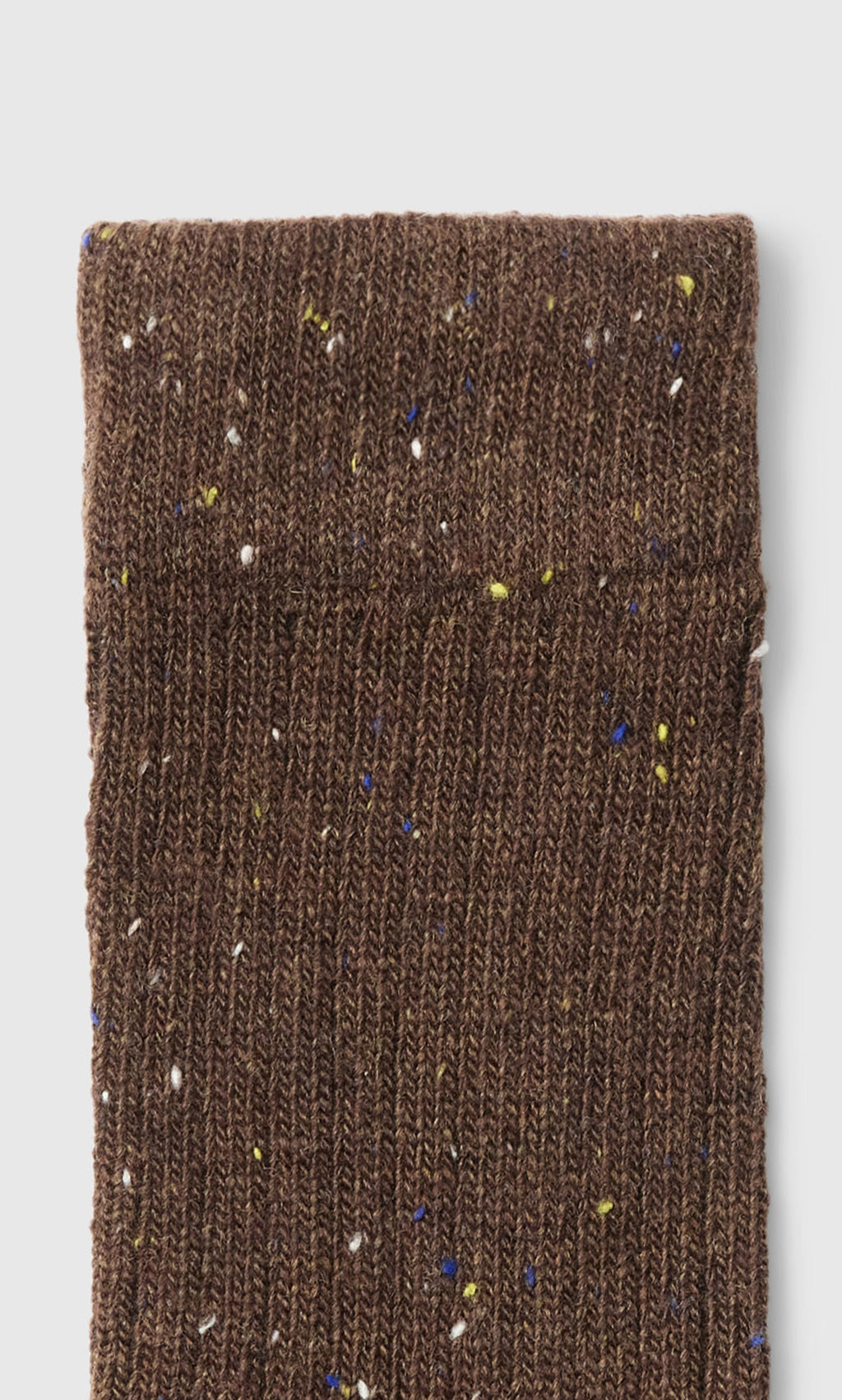 Plümo  Brown Speckled Socks: close-up of rib-knit brown socks with blue, yellow, and white speckles.
