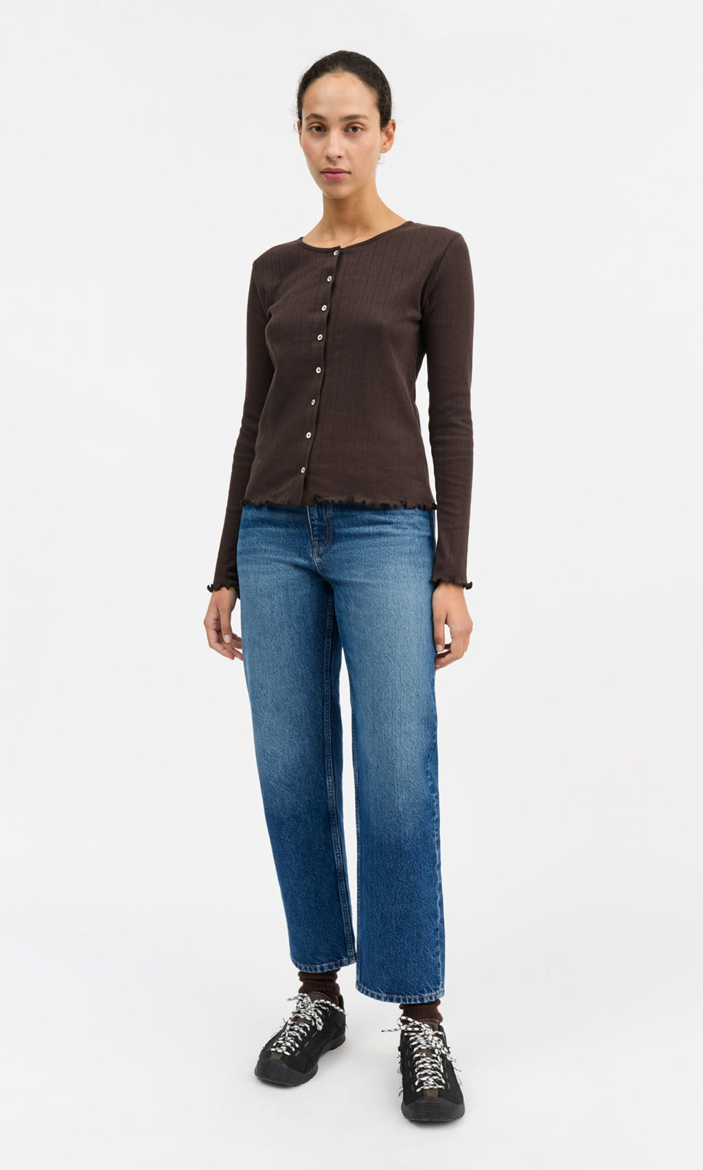 Plümo- Someone wears the Eddie Cardigan in brown, blue jeans, and black sneakers against a white background.