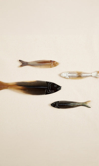 Plümo  Four colorful fish bone designs form the unique Sardine Comb, styled on a plain beige background.