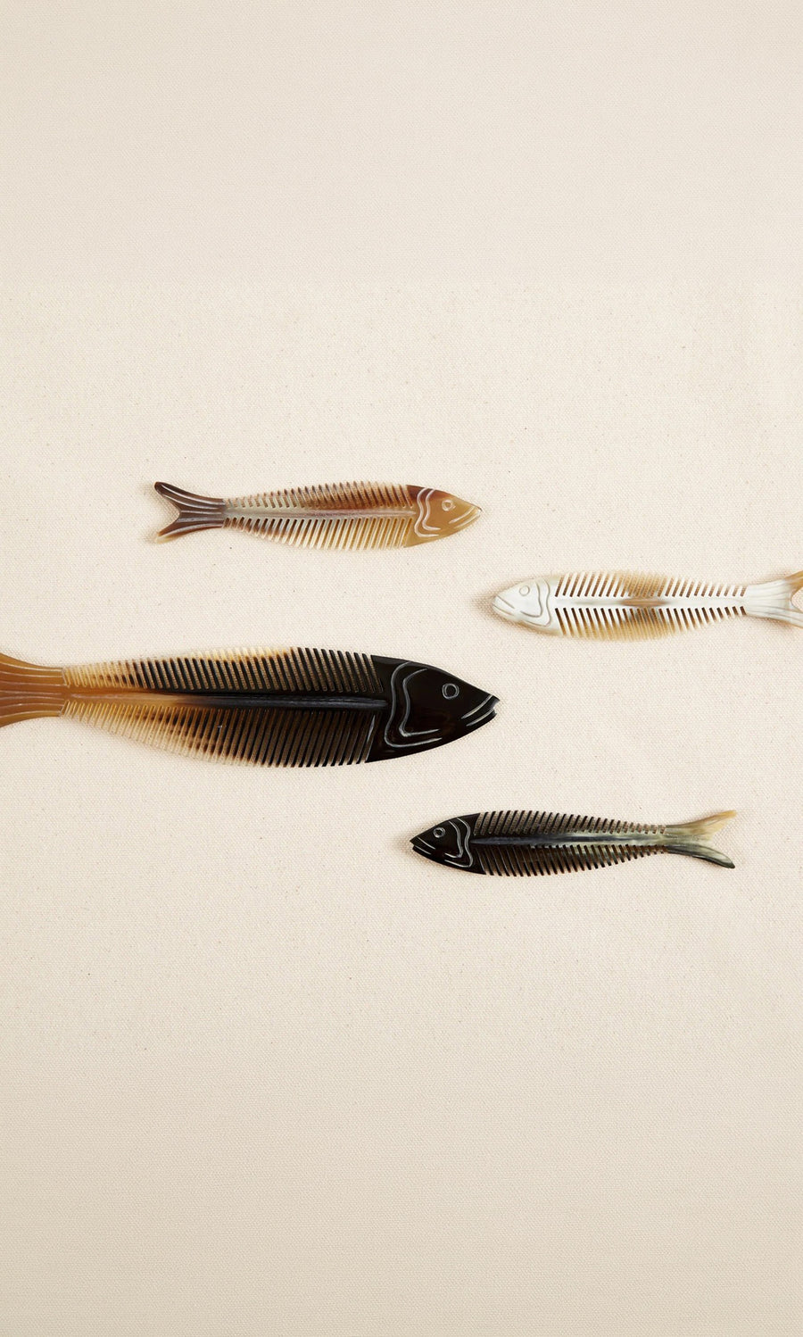 Plümo  Four colorful fish bone designs form the unique Sardine Comb, styled on a plain beige background.