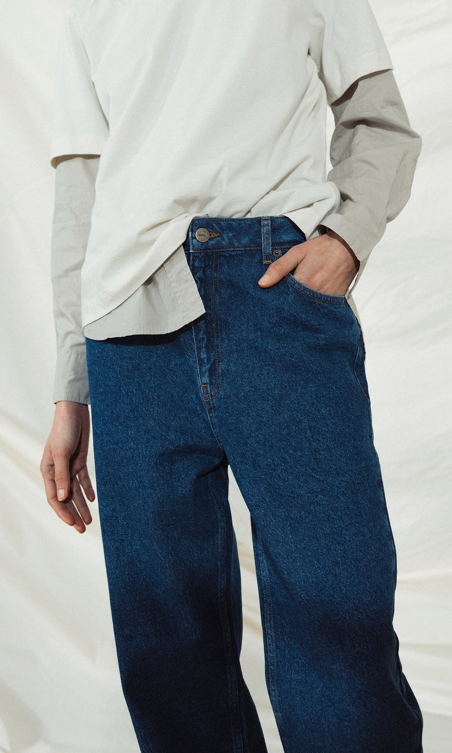 Plümo- Person wears Carlo Jeans with a white long-sleeve shirt under a tee, one hand tucked in the pocket.