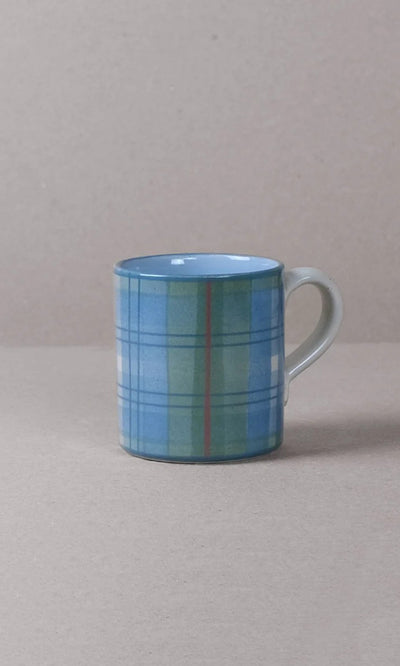 Plümo  Blue Tartan Mug with handle, handmade and inspired by the Scottish Highlands, on a beige surface.
