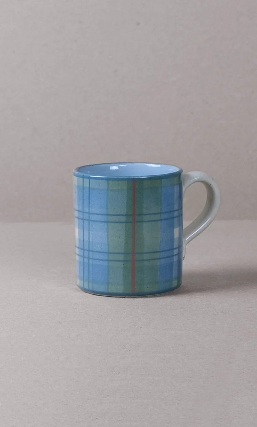 Plümo  Blue Tartan Mug with handle, handmade and inspired by the Scottish Highlands, on a beige surface.