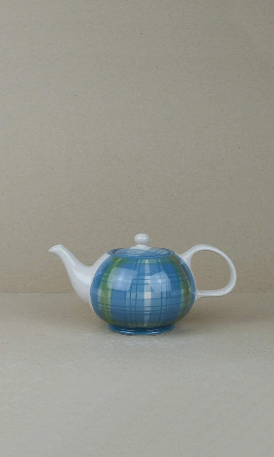 Plümo  Tartan Teapot in blue and green plaid with a white handle and spout, set against a plain beige background.