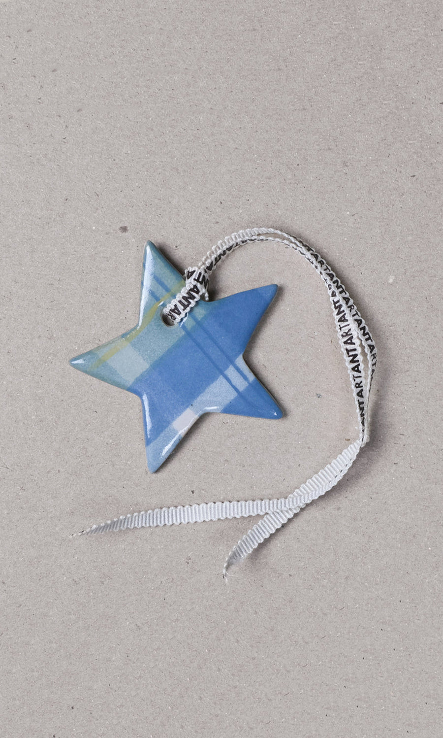 Plümo  Tartan Star Decoration: handcrafted blue ceramic star with plaid pattern and white ribbon on gray background.