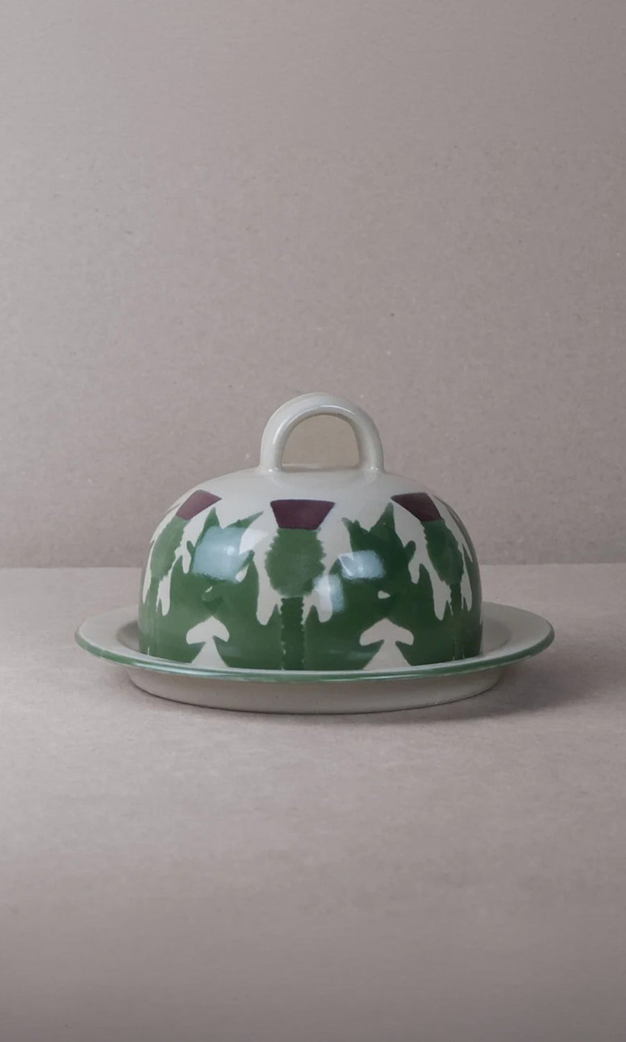 Plümo  Thistle Cheese Dome: Hand-painted ceramic with thistle design and handle, set on a plain background.