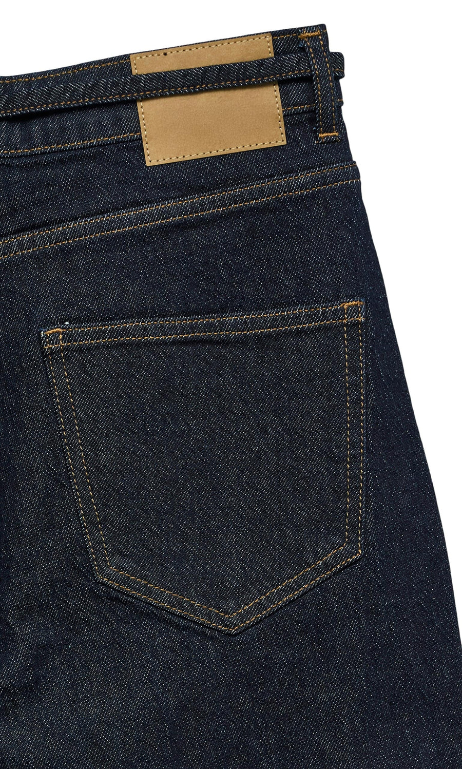 Plümo- Close-up of the back pocket and waistband of Belted Wide Jeans in dark blue denim with tan leather patches.