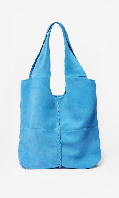 Plümo- The Alves Bag is bright blue suede with whip stitch seams and wide handles, shown against a white background.