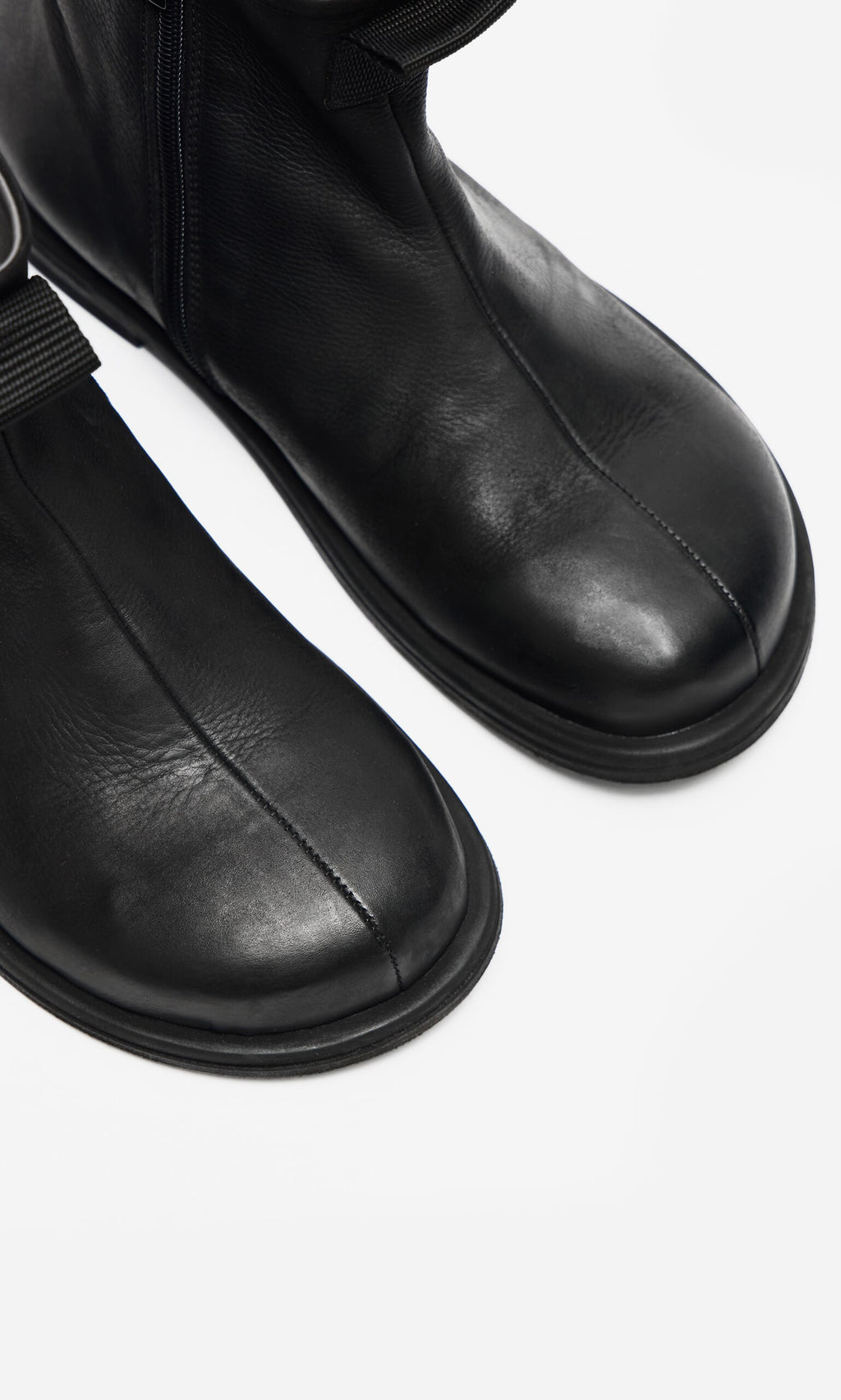 Plümo- Close-up of Ancona Boots in black waxy leather with round toes and visible stitching on a white background.