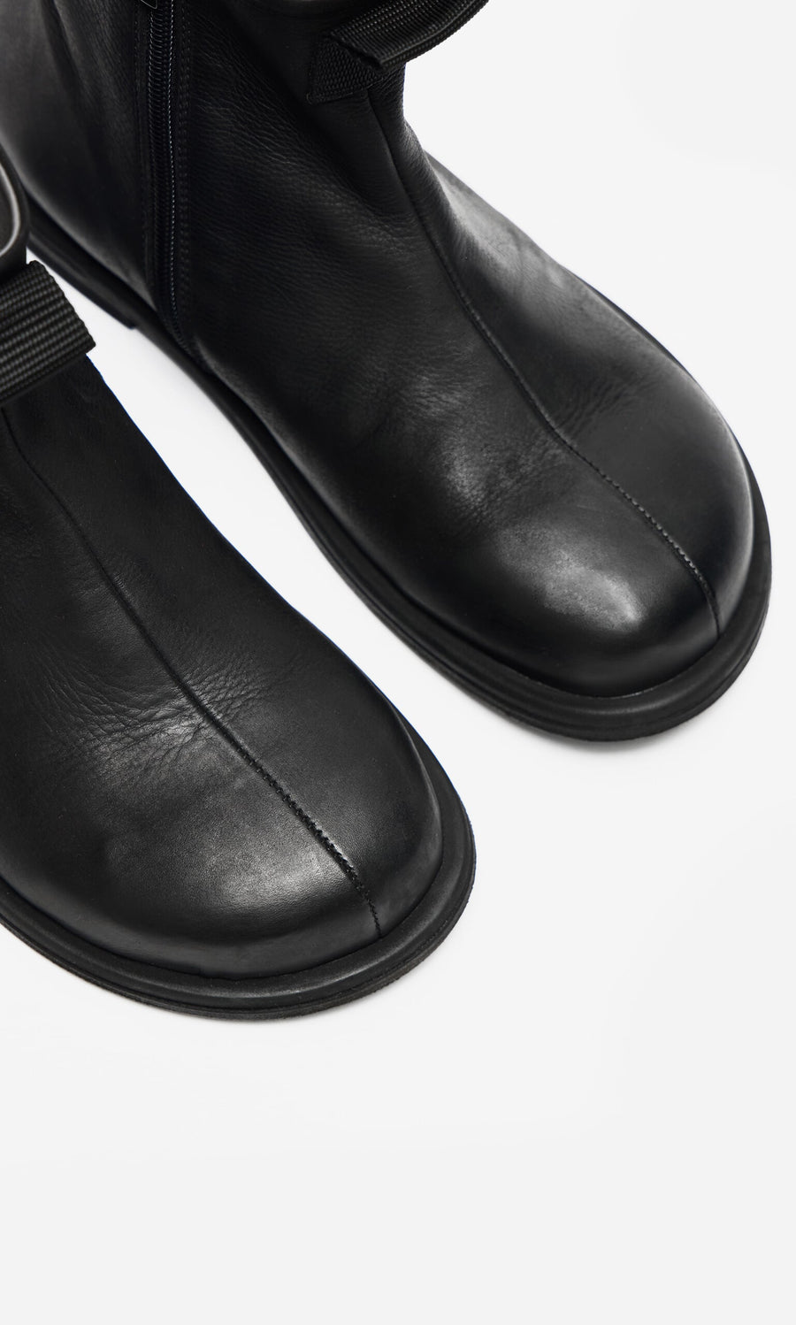 Plümo- Close-up of Ancona Boots in black waxy leather with round toes and visible stitching on a white background.