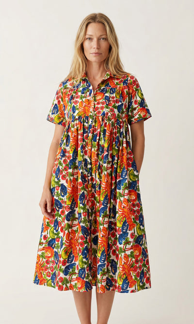 Plümo  Woman in the Astice Dress: a colorful, hand-printed cotton voile with short sleeves and bold floral patterns.
