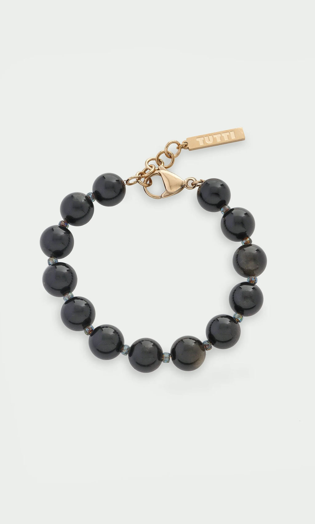 Plümo- Obsidian Bracelet with gold clasp and Tutti tag, shown on white—stylish healing jewelry.