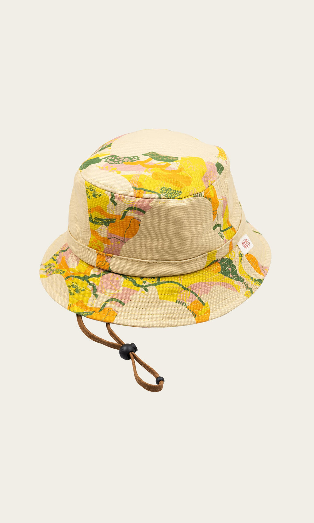 Plümo- Camo Bucket Hat: Beige canvas with yellow, green, and pink abstract pattern and an adjustable brown chin strap.