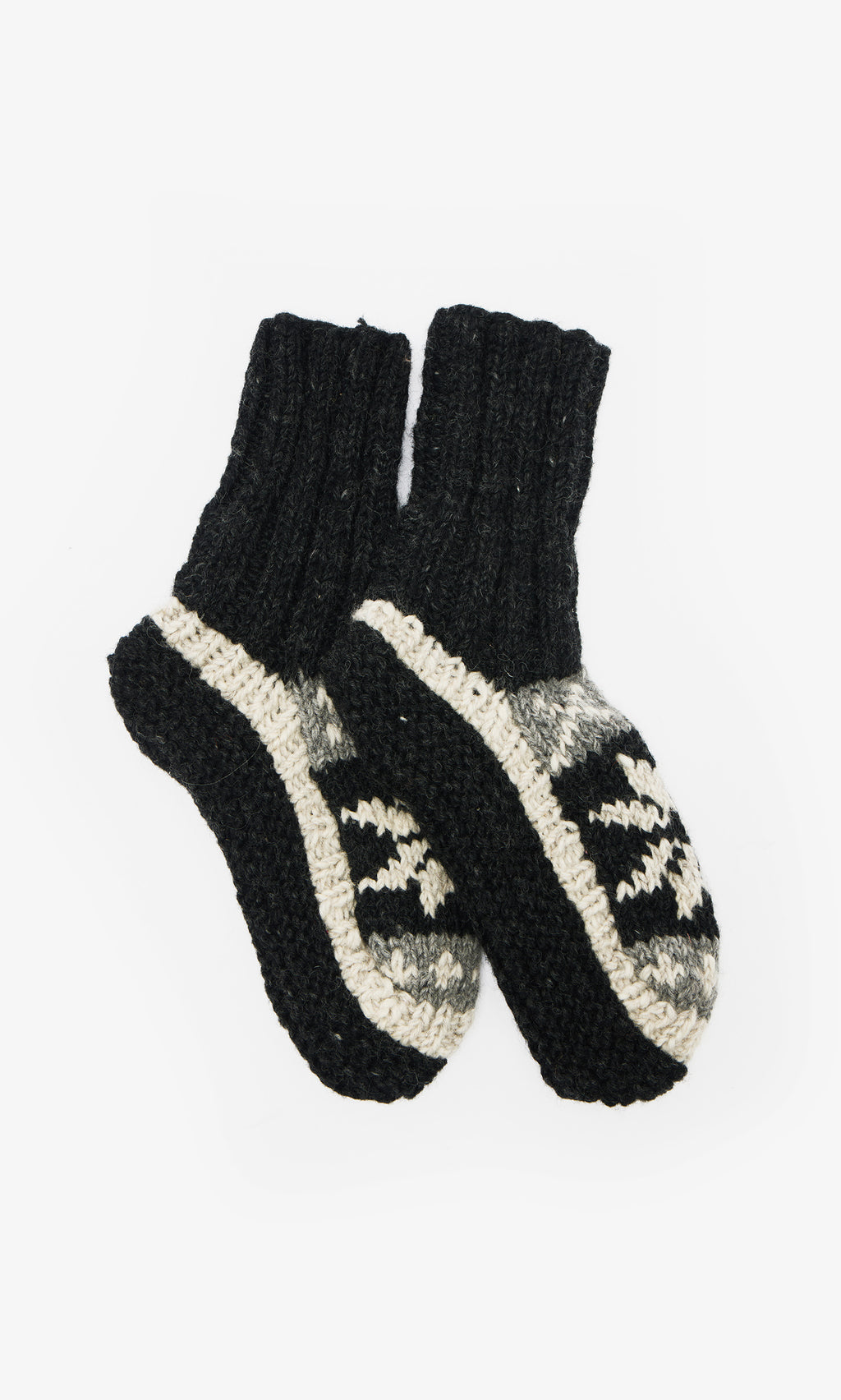 Plümo  Nordic Star Slipper Socks: hand-knitted wool, black cuffs and soles, gray and black geometric pattern on the foot.
