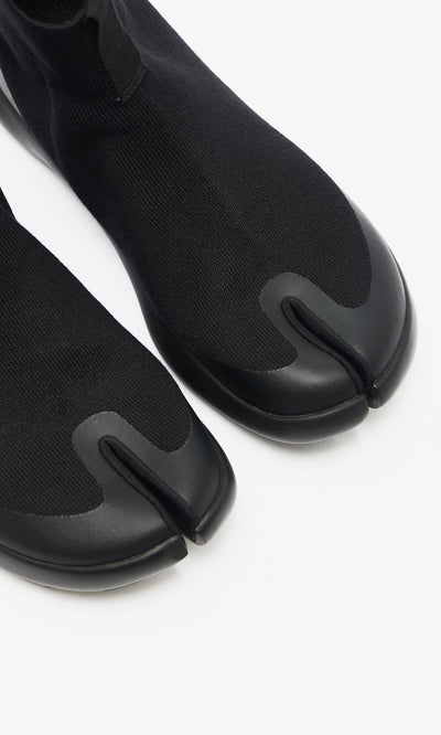 Plümo  Higher Tabi Boots in black feature a knit upper, rubber sole, and split-toe design, shown from above on white.