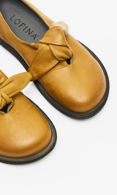 Plümo  Close-up of handcrafted Amber Leather Shoes with knotted detail, black soles, and LOFINA Danish design on insole.