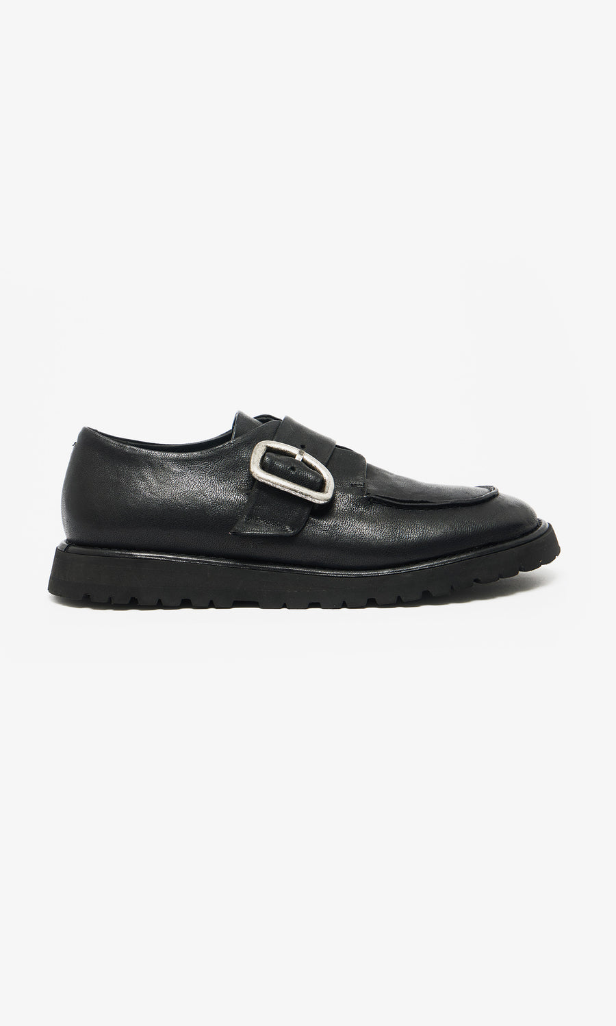 Plümo  Black Creepers feature black leather, a thick lugged rubber sole, and a large silver buckle on a white background.