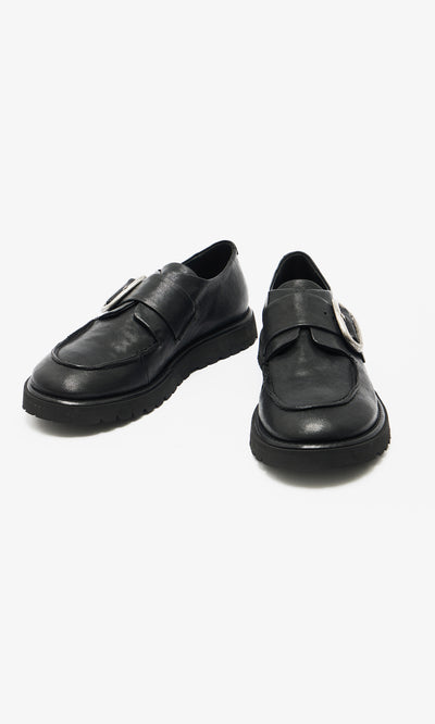 Plümo  A pair of black leather creepers with thick soles and a large silver buckle on each shoe.