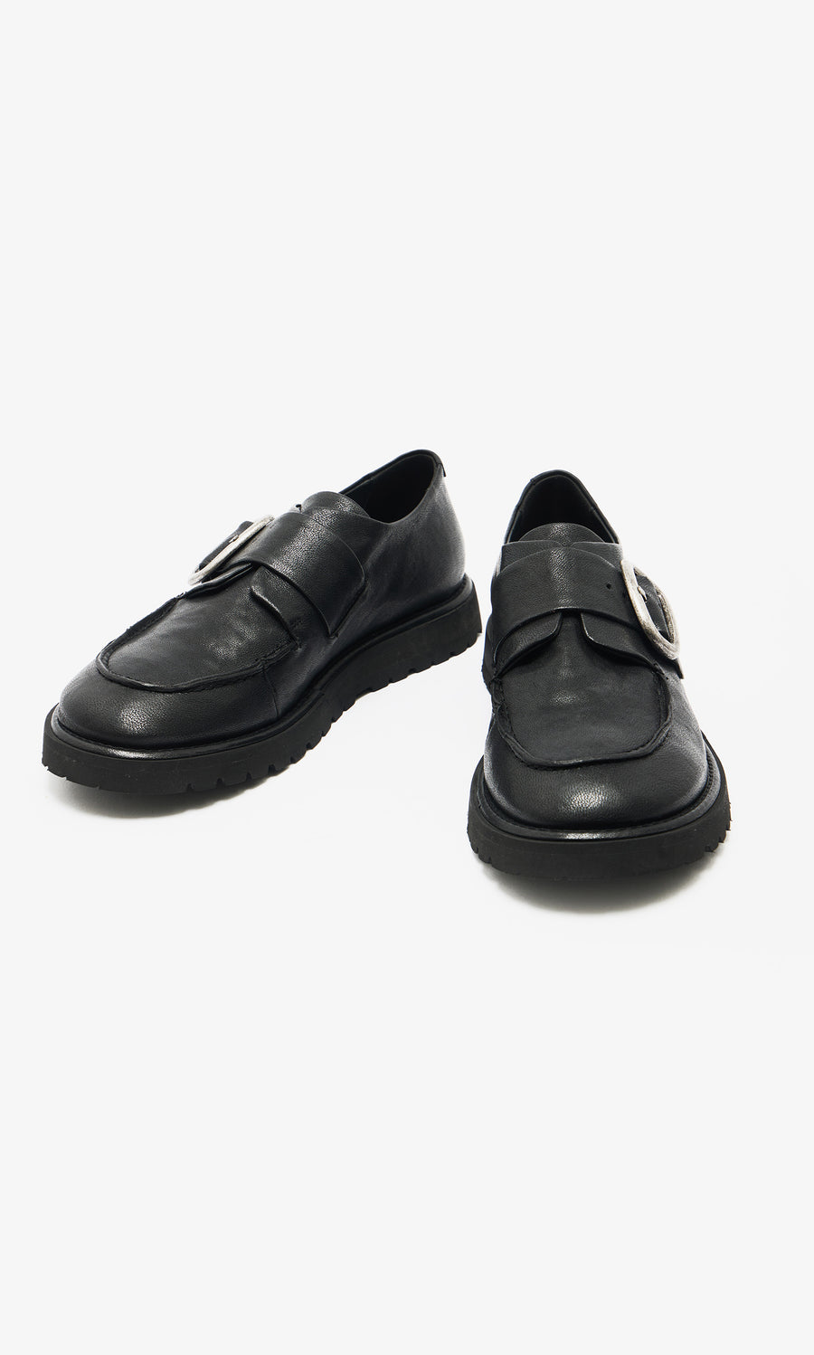 Plümo  A pair of black leather creepers with thick soles and a large silver buckle on each shoe.