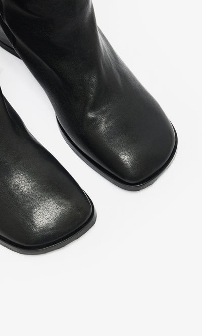 Plümo  Close-up of Briony Boots—knee-high black leather with hidden internal wedge—on a white background.