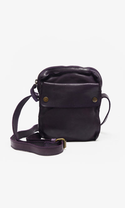 Plümo  Loyd Bag: Small dark purple leather pouch with front pocket, brass buttons, and adjustable strap for versatile wear.