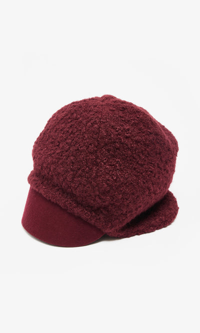 Plümo  Velo Wool Cap: Textured maroon boucle hat with firm brim, rounded crown, Parisian newsboy style on white.
