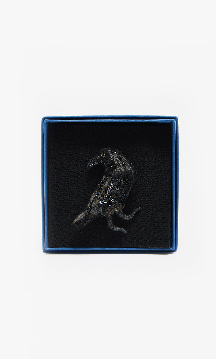 Plümo  The Black Raven Brooch is a handmade bird-shaped pin, elegantly presented in a blue box with a soft black interior.