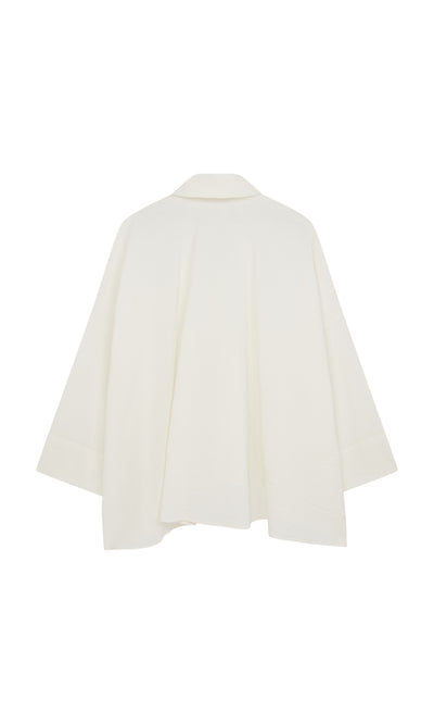 Plümo  Back view of the Laundered Shirt—a loose, textured cotton jacket with wide collar and flared hem, artist’s smock-inspired.