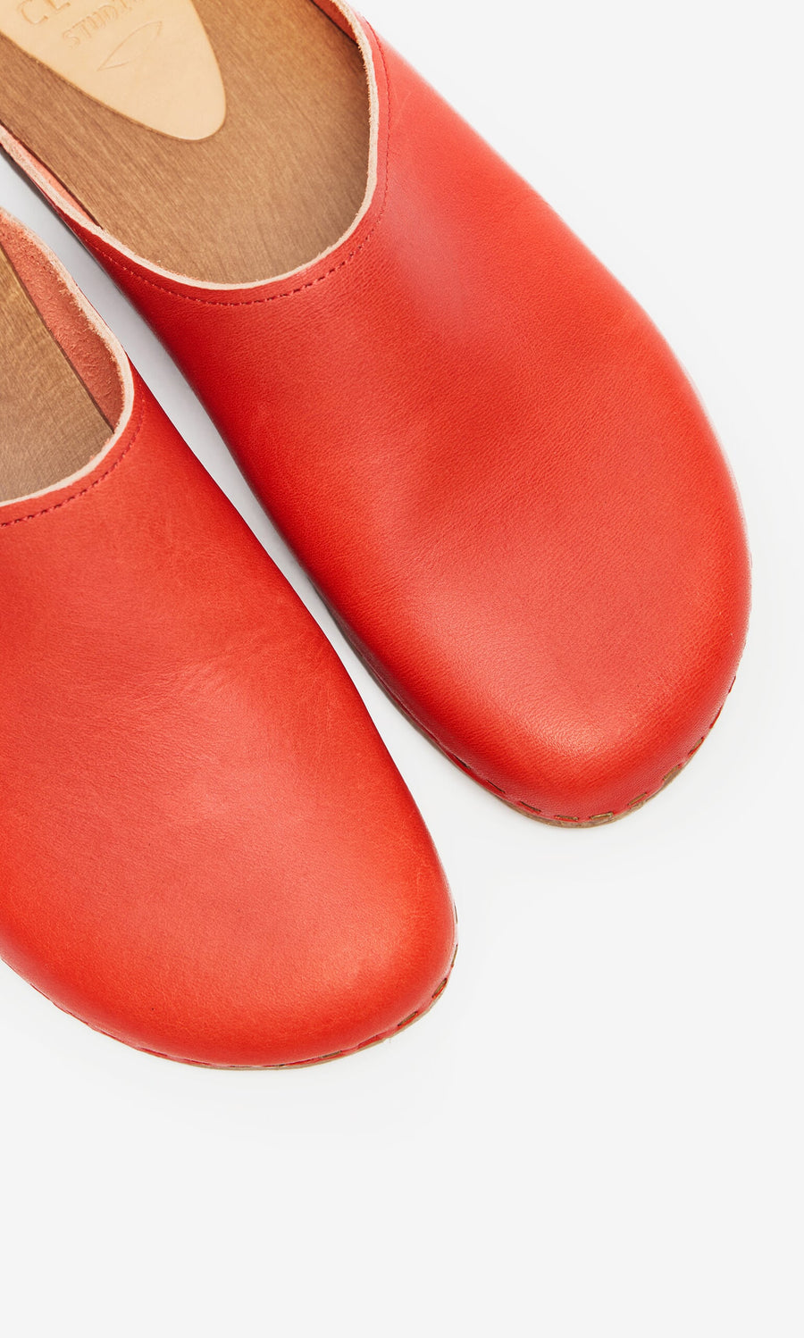 Plümo- Close-up of Carlie Clogs: red leather Swedish clogs with tan insoles, crafted from vegetable-tanned leather.