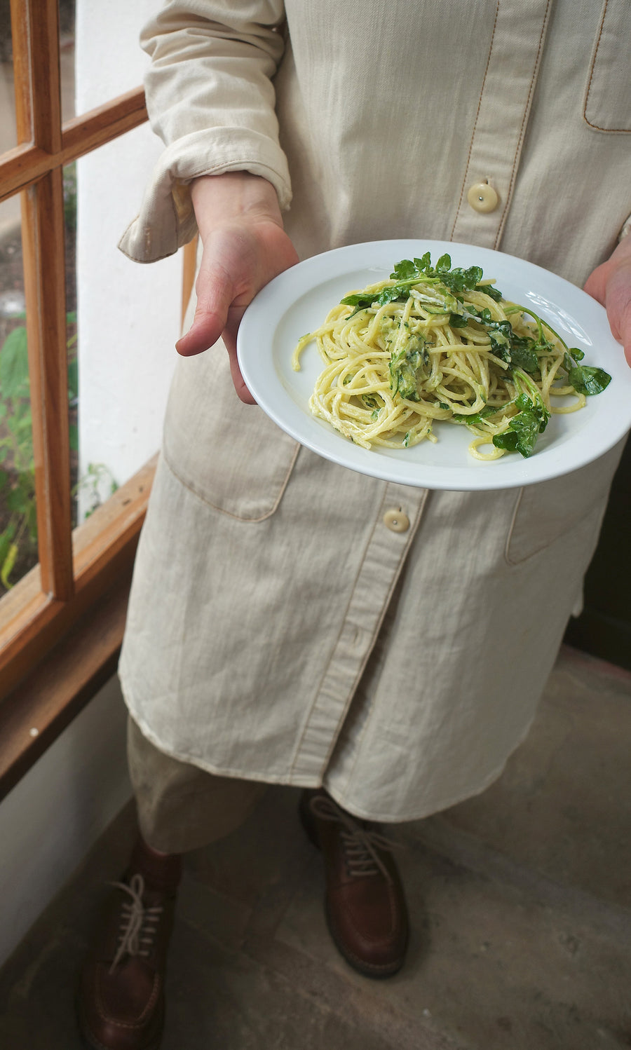 Plümo  Person in beige holds a plate of spaghetti with greens from Vegetable Recipes By Jess Dennison.