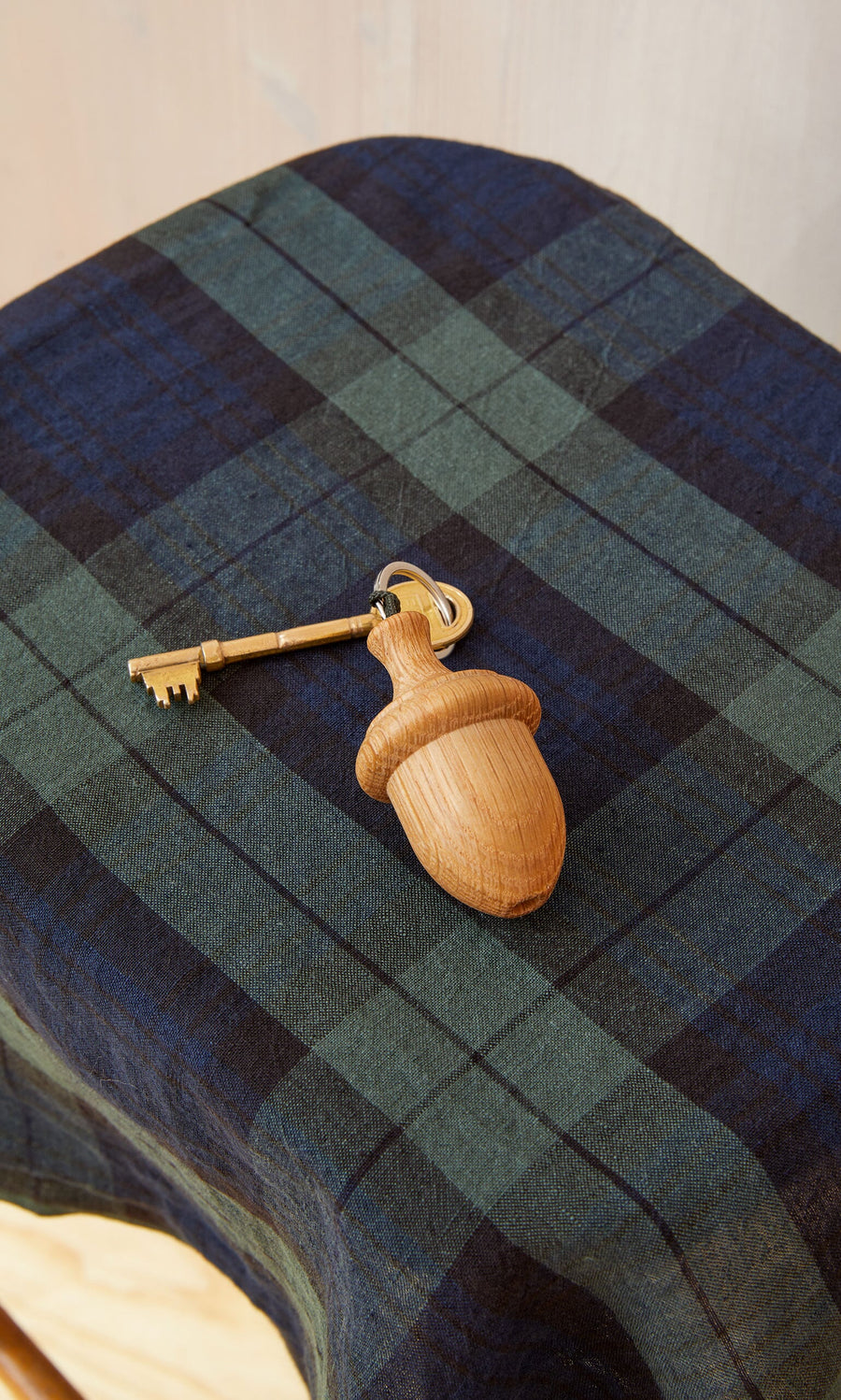Plümo- An Acorn Keyring with a vintage key rests on green and blue plaid fabric.