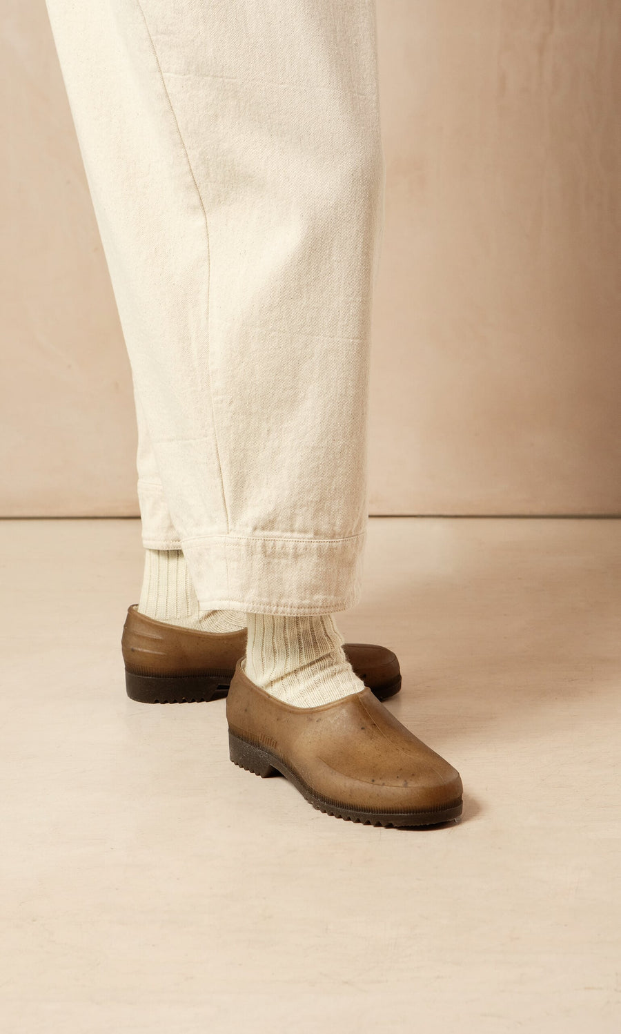 Plümo- Person wearing cream pants, cream socks, and Hemp Clogs, standing on a light-colored floor.