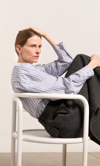 Plümo  Woman in a striped shirt rests her head, wearing Infinity Earrings that catch the light.