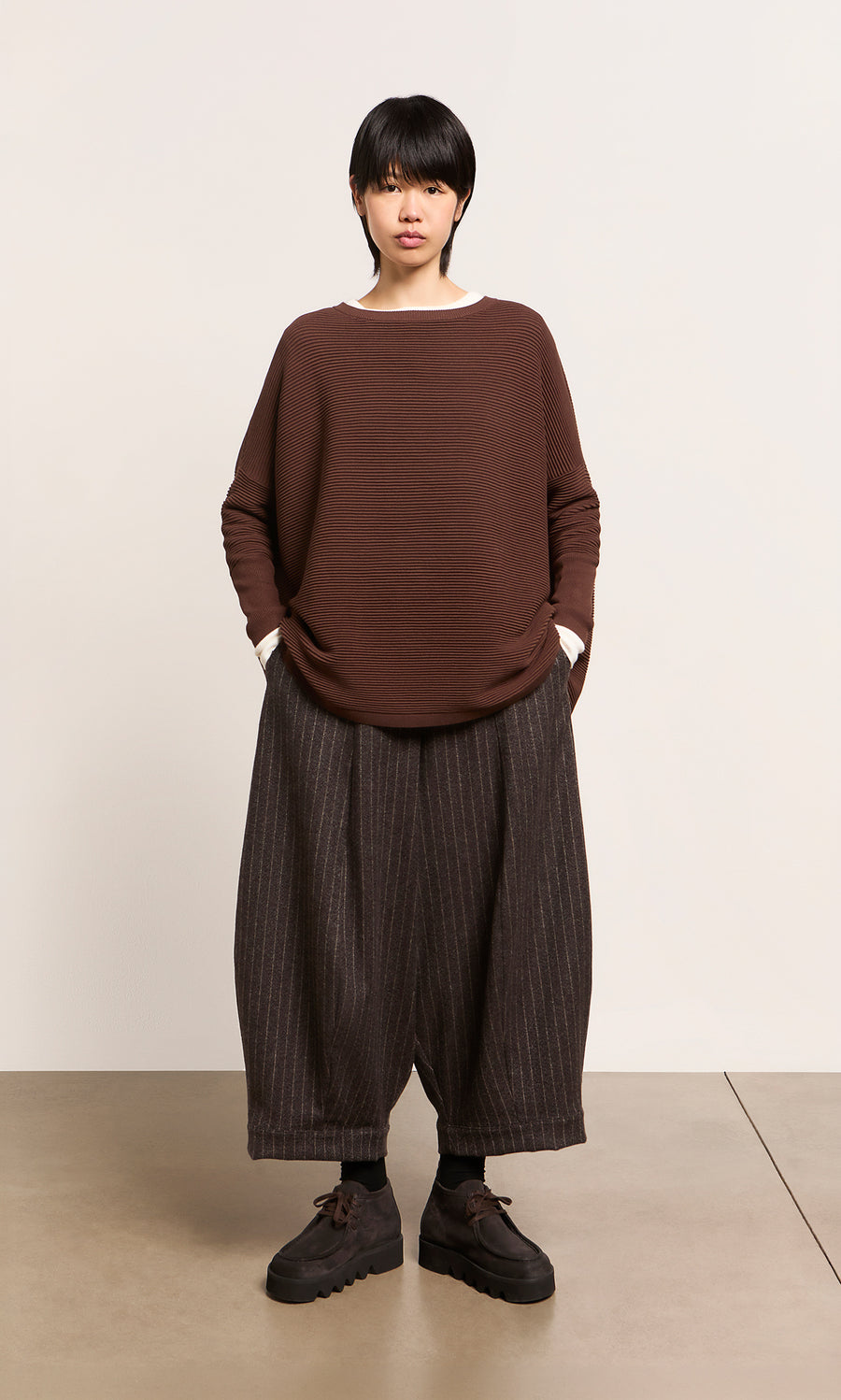 Plümo  Wearing the Jack Sweater - Bitter Chocolate from Plümo Studio, pinstriped pants, and black shoes.