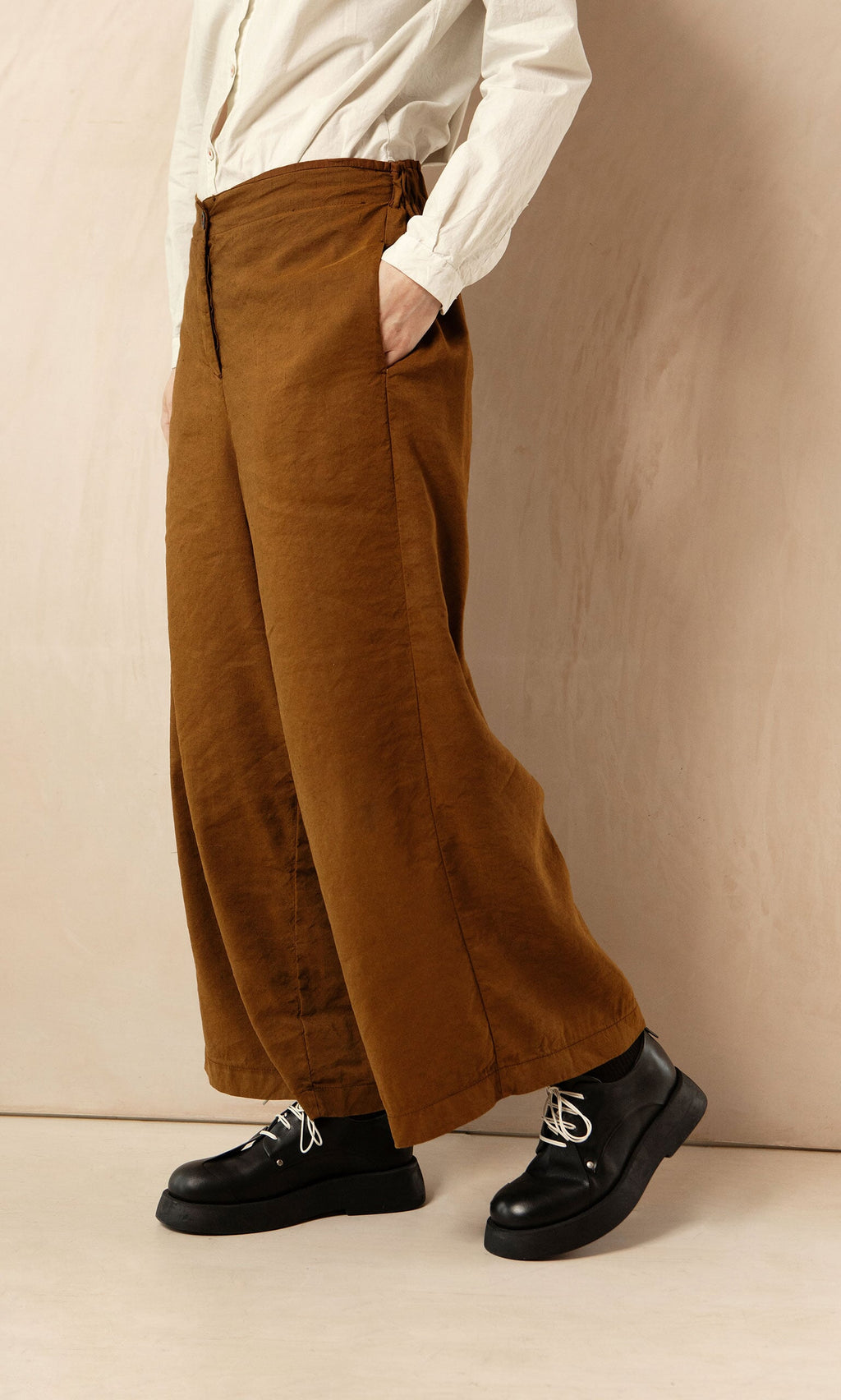 Plümo- Model wears Kapur Pants with a white shirt and black shoes, styled against a beige background for a flattering look.