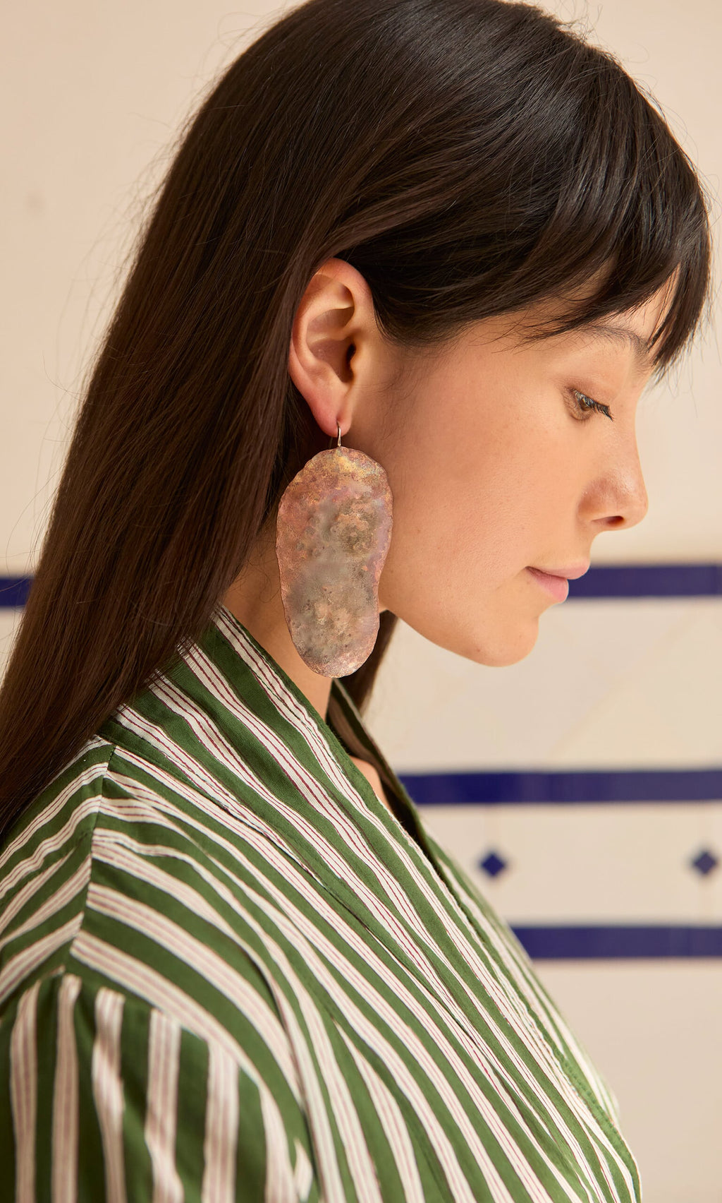 Plümo- A woman in a green striped shirt wears Large Chroma Earrings, shown from the side.