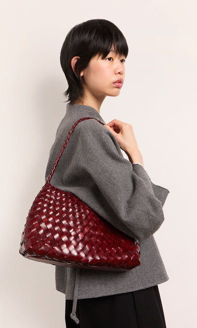 Plümo  Person in a gray jacket holds the Moone Bag, a hand-woven leather bag made in South Africa, over their shoulder.