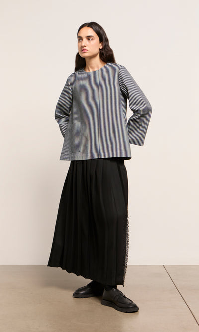 Plümo  Person in a Norfolk Top, long black skirt, and black loafers stands against a neutral background.