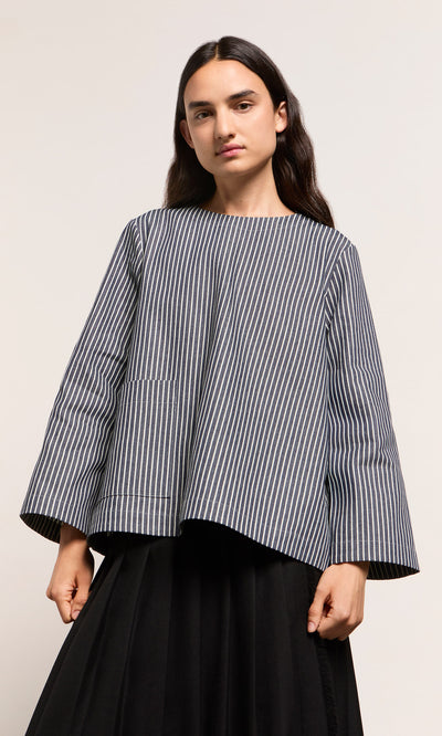 Plümo  Person wearing a loose Norfolk Top in navy and white stripes with a black skirt, standing against plain background.