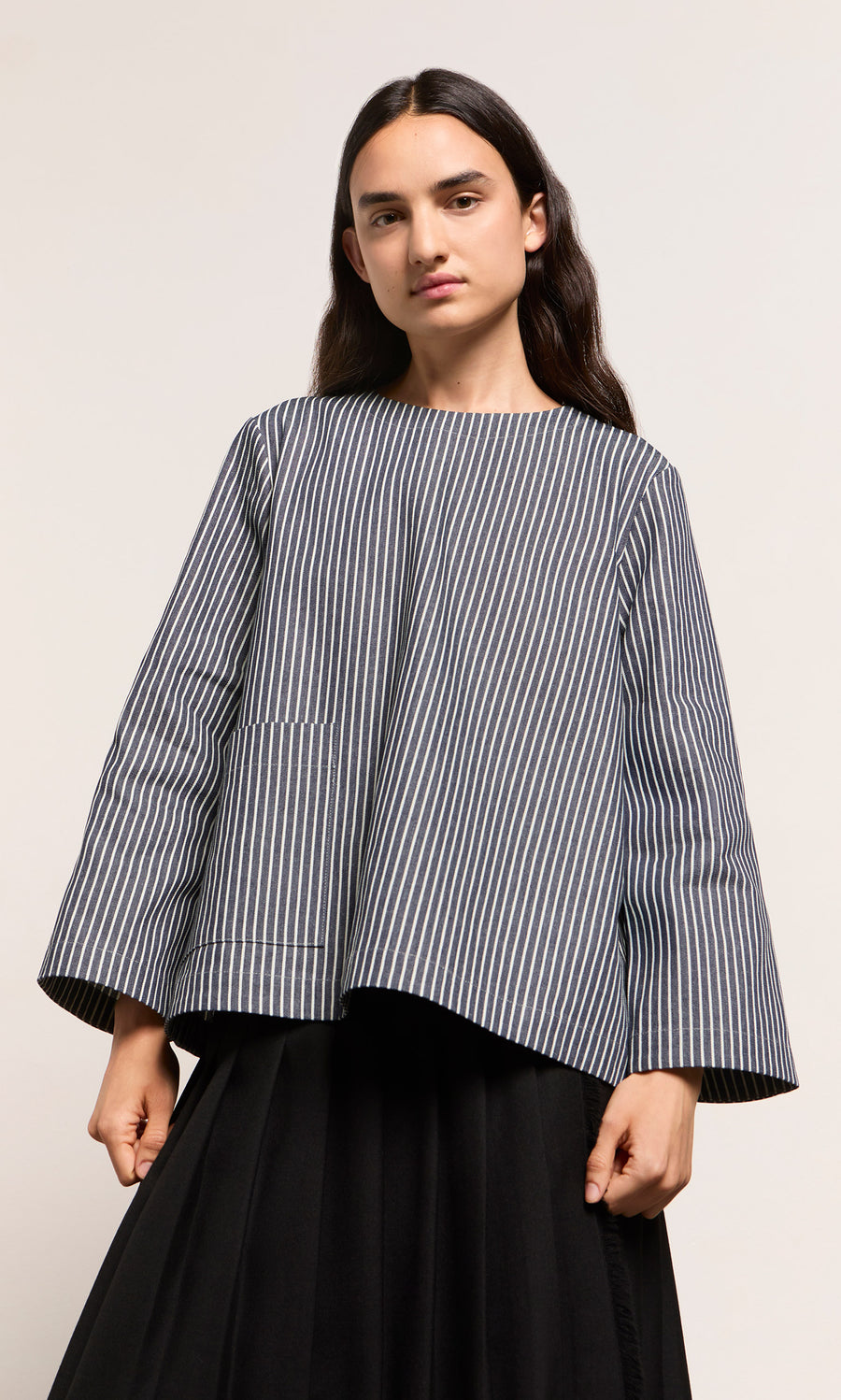 Plümo  Person wearing a loose Norfolk Top in navy and white stripes with a black skirt, standing against plain background.