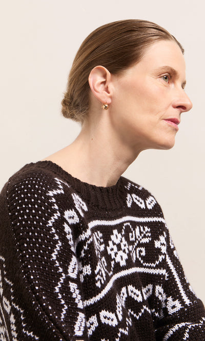 Plümo  Woman in profile wears Ora Earrings, black and white sweater, hair tied back, on a neutral background.