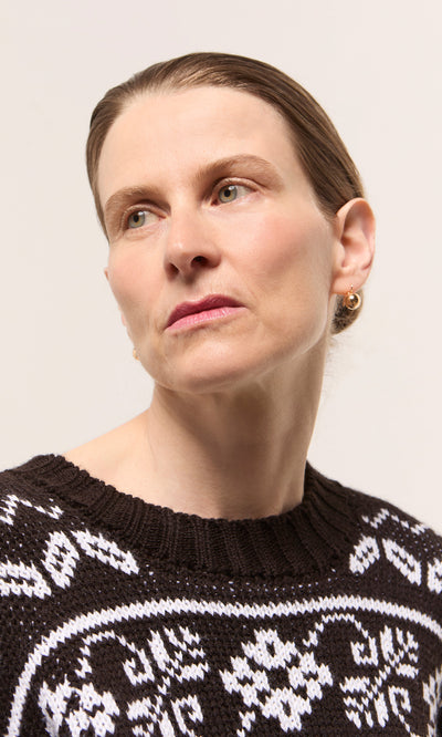 Plümo  Light-skinned woman with brown hair wears Ora Earrings and a patterned black and white sweater.