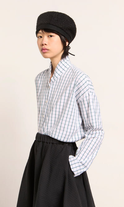 Plümo  Wearing a black hat, checked shirt, and skirt—showcasing the Perinne Beret, a handmade adjustable Parisian style.
