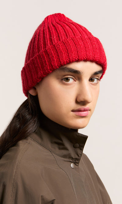 Plümo  Model in Red Breton Beanie and brown jacket, gazing to the side with a neutral expression.