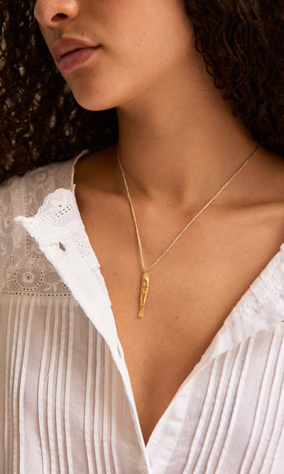 Plümo- A woman in a white blouse wears the Sardine Necklace; only her lower face and neck are visible.