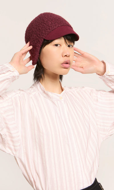 Plümo  Person in a striped shirt and Velo Wool Cap poses playfully against a light background.