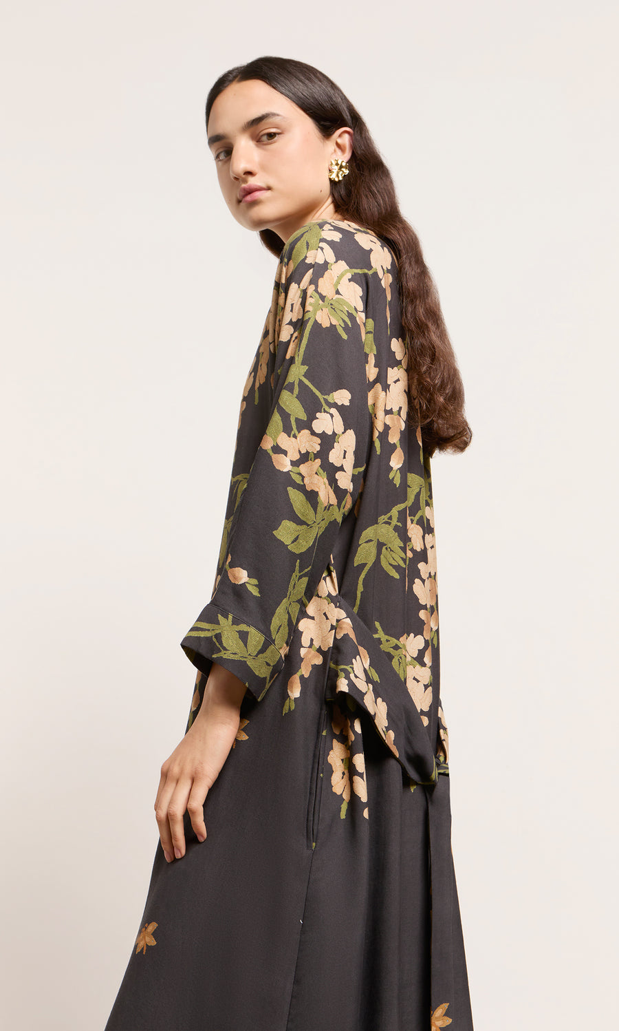 Plümo  Person in a Whisteria Dress, standing sideways against a plain, light background.