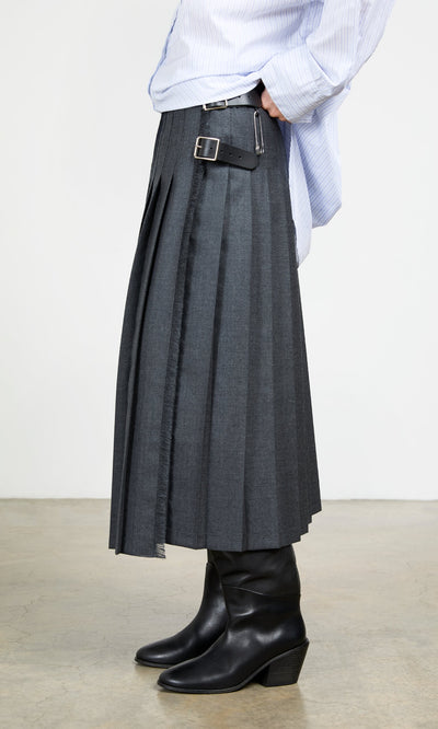 Plümo- Wearing the Boyd Kilt in grey worsted wool with side buckles, black boots, and a light blue shirt indoors.