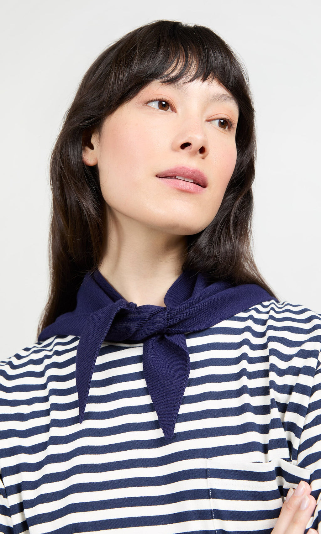 Plümo- Woman in a blue and white striped top with a Jona Necktie - Navy draped around her neck, looking slightly upward.